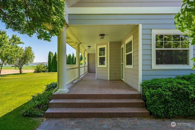 entrance to property with a lawn and covered porch