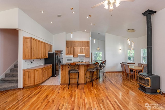 kitchen featuring oven, a wood stove, black refrigerator with ice dispenser, and tasteful backsplash