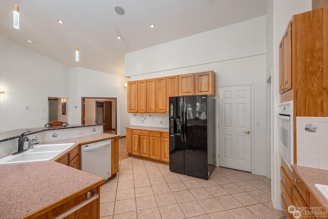 kitchen with white appliances, sink, light tile patterned floors, and vaulted ceiling