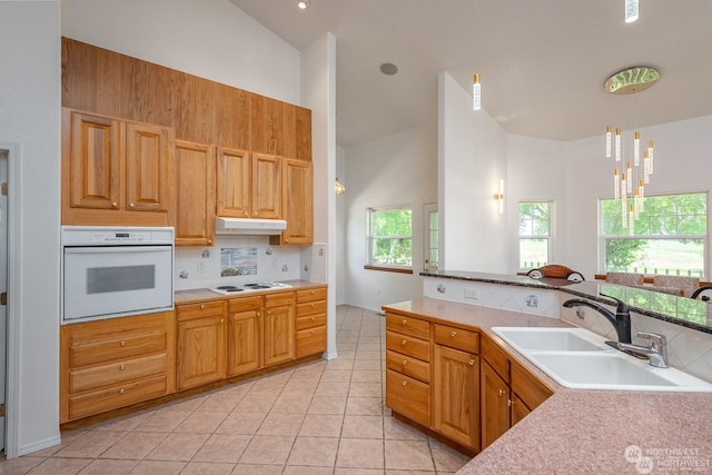 kitchen with white appliances, high vaulted ceiling, an inviting chandelier, sink, and light tile patterned floors