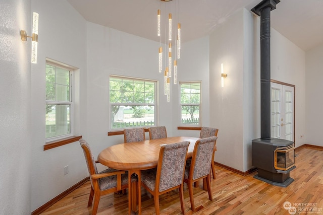 dining space featuring a high ceiling, light hardwood / wood-style flooring, and a wood stove