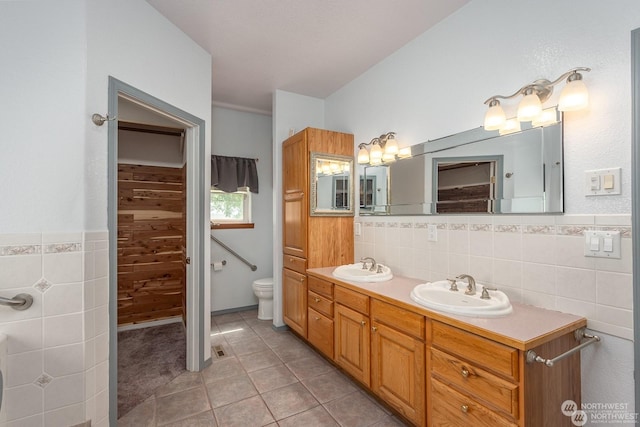 bathroom with tile patterned flooring, vanity, tile walls, and toilet