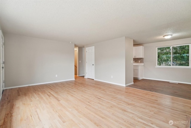 unfurnished living room with a textured ceiling and light hardwood / wood-style flooring