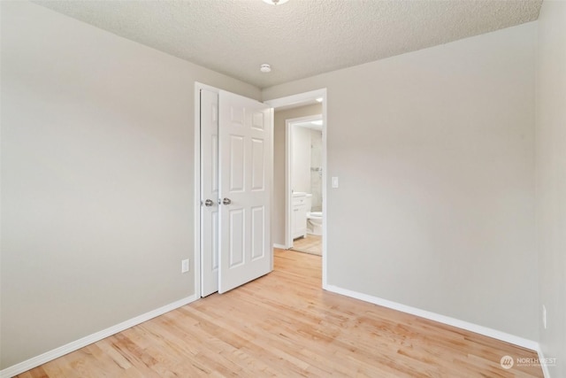 empty room with a textured ceiling and light wood-type flooring