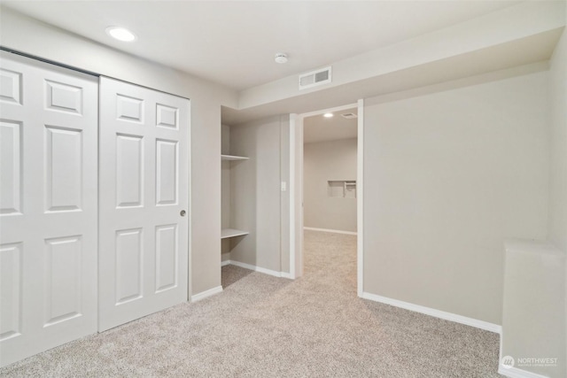 unfurnished bedroom with light colored carpet and a closet