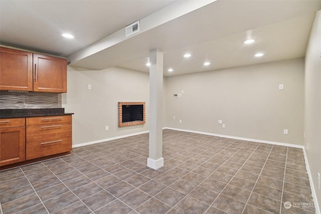 basement with a fireplace and dark tile patterned flooring