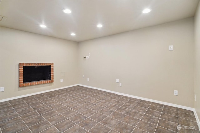 basement featuring dark tile patterned floors and a fireplace