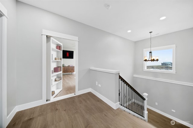 hallway featuring hardwood / wood-style flooring and an inviting chandelier