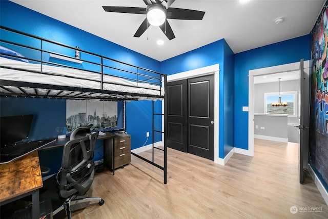 bedroom featuring ceiling fan with notable chandelier, light wood-type flooring, and a closet