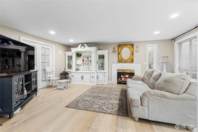 living room featuring light wood finished floors, a fireplace with flush hearth, and recessed lighting