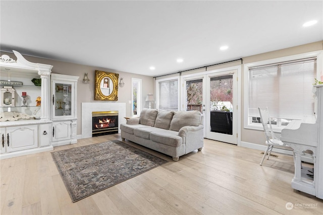 living room featuring a fireplace with flush hearth, a wealth of natural light, light wood finished floors, and recessed lighting