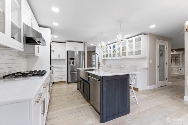 kitchen featuring appliances with stainless steel finishes, extractor fan, light wood-style flooring, and a notable chandelier