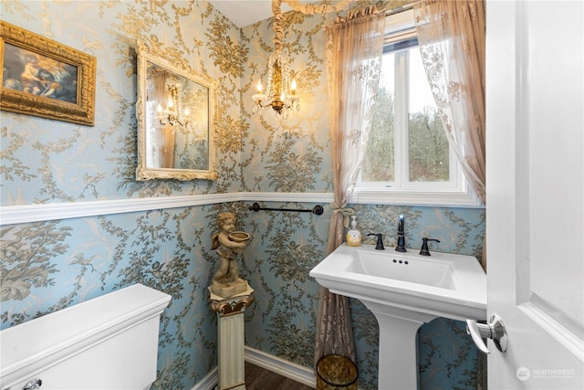 half bath with toilet and wallpapered walls