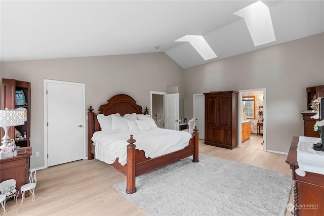 bedroom with vaulted ceiling with skylight, connected bathroom, and light wood-style flooring