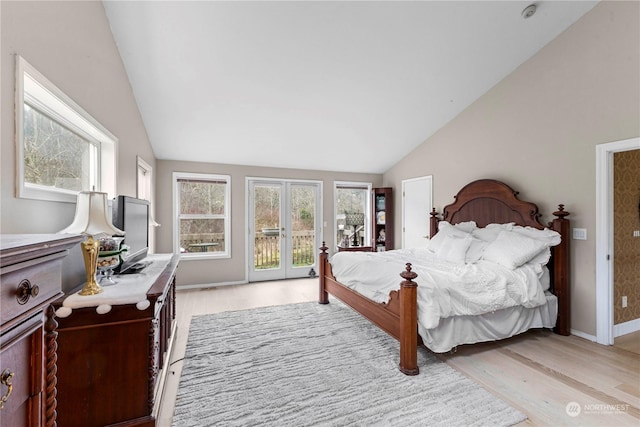 bedroom with vaulted ceiling, access to outside, multiple windows, and light wood-style floors