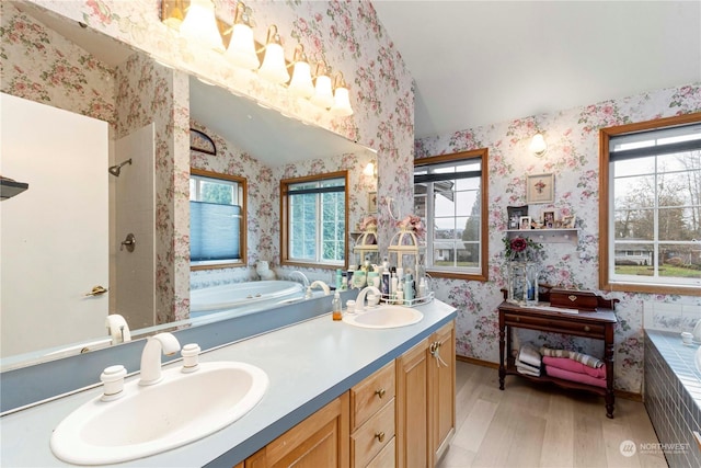 full bathroom featuring wood finished floors, vaulted ceiling, a sink, and wallpapered walls