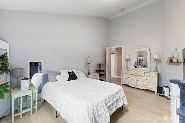 bedroom featuring a towering ceiling and light wood finished floors