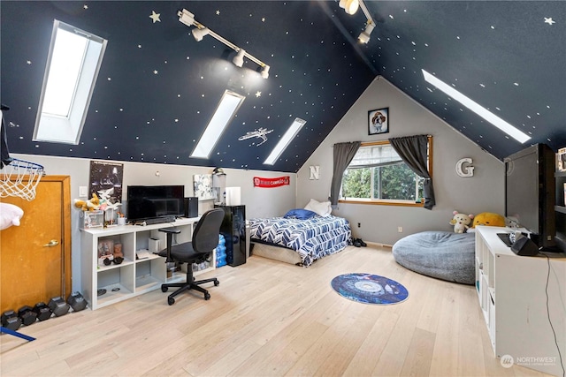 bedroom with vaulted ceiling with skylight, wood finished floors, and rail lighting