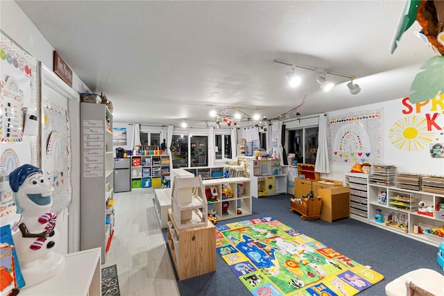 recreation room featuring a textured ceiling and track lighting