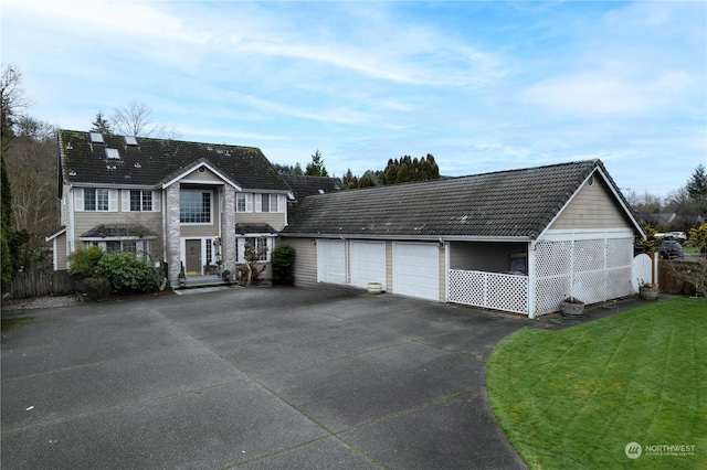 view of front facade featuring driveway, an attached garage, a tile roof, and a front yard