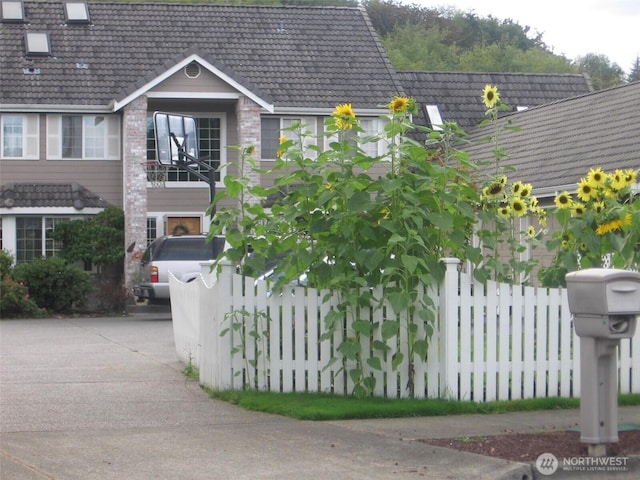 exterior space with a tile roof, fence, and driveway