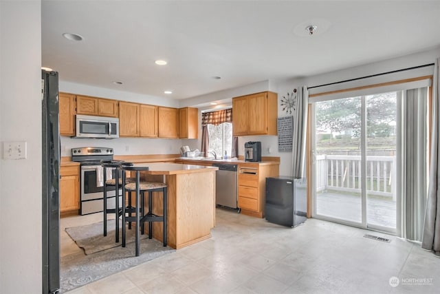 kitchen featuring a kitchen bar, stainless steel appliances, and a kitchen island