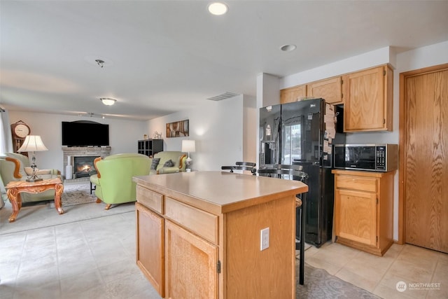 kitchen with a kitchen island, black refrigerator with ice dispenser, and light brown cabinets