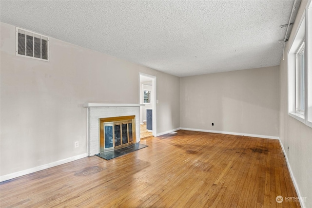 unfurnished living room with wood-type flooring, a textured ceiling, and a healthy amount of sunlight