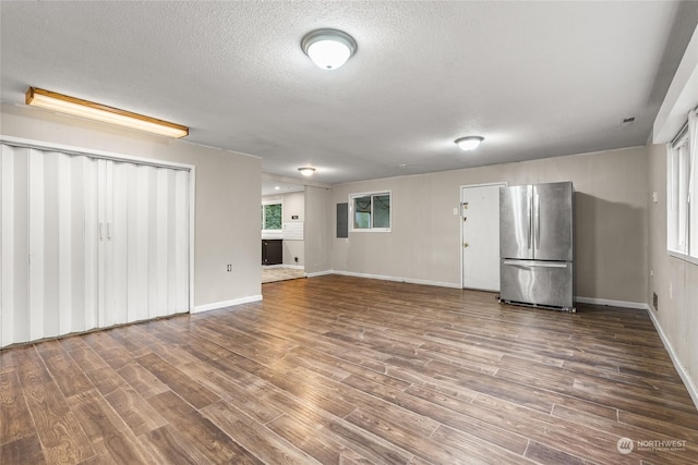 unfurnished living room featuring electric panel, a textured ceiling, and hardwood / wood-style flooring