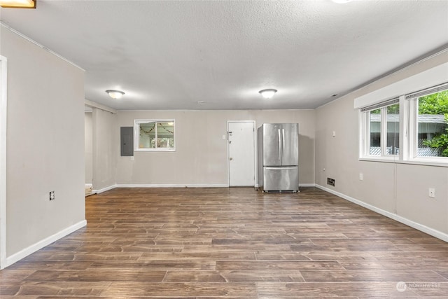 unfurnished living room with electric panel, a textured ceiling, and hardwood / wood-style flooring