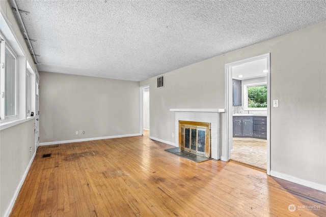 unfurnished living room with a textured ceiling, light hardwood / wood-style flooring, and sink