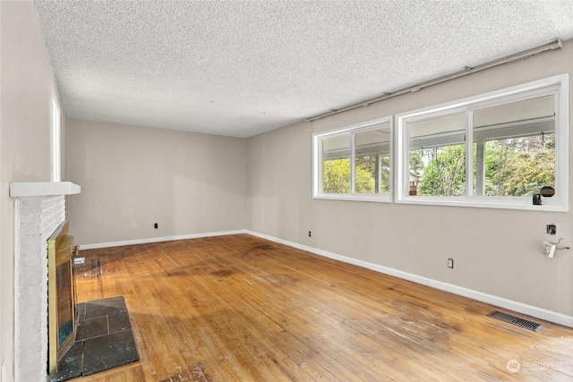 unfurnished living room featuring hardwood / wood-style floors, a fireplace, and a textured ceiling