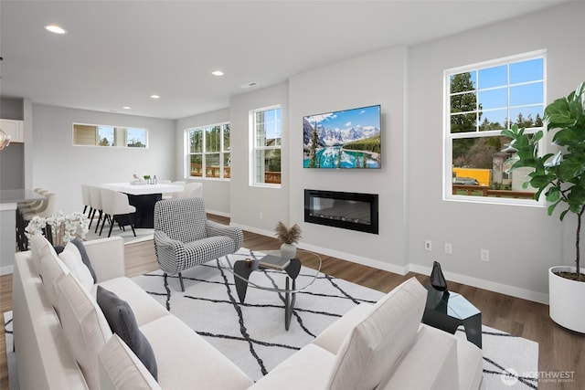 living room with recessed lighting, baseboards, wood finished floors, and a glass covered fireplace