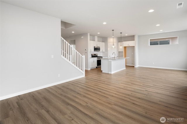 unfurnished living room featuring light wood-type flooring, visible vents, and baseboards