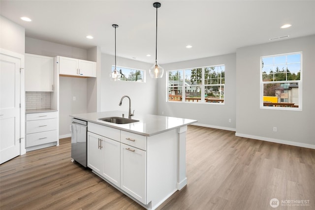 kitchen featuring visible vents, a sink, decorative backsplash, dishwasher, and light wood-type flooring