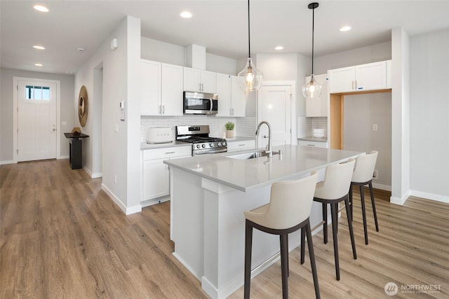 kitchen with white cabinets, light wood-type flooring, appliances with stainless steel finishes, and a sink