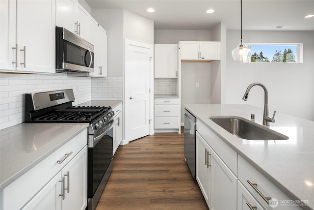 kitchen featuring dark wood-style flooring, appliances with stainless steel finishes, white cabinetry, and a sink