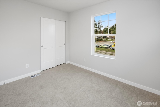 unfurnished bedroom featuring a closet, baseboards, visible vents, and carpet floors