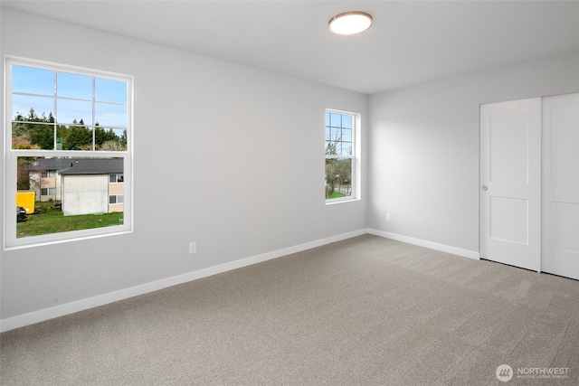 carpeted empty room featuring baseboards