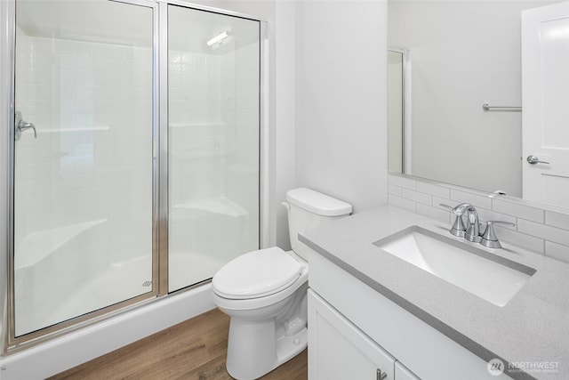 full bath with vanity, wood finished floors, a stall shower, toilet, and backsplash