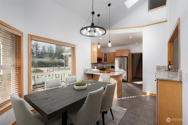 tiled dining room featuring a skylight, an inviting chandelier, and high vaulted ceiling