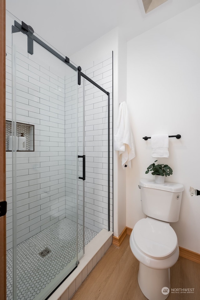 bathroom featuring a shower with door, toilet, and hardwood / wood-style flooring