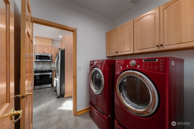 clothes washing area with washer and dryer and cabinets