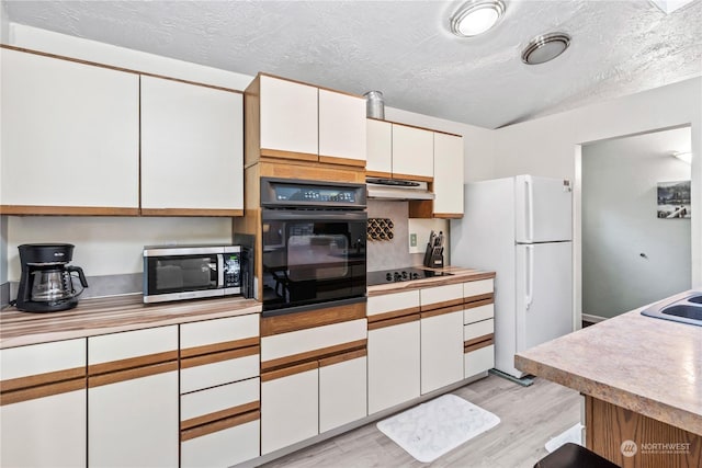 kitchen with white cabinets, a textured ceiling, black appliances, and light hardwood / wood-style flooring