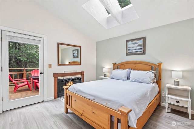 bedroom with lofted ceiling with skylight, access to outside, and hardwood / wood-style flooring