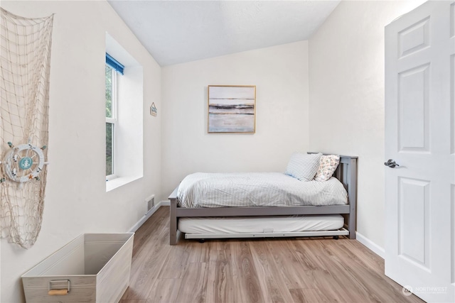 bedroom featuring light hardwood / wood-style flooring and vaulted ceiling