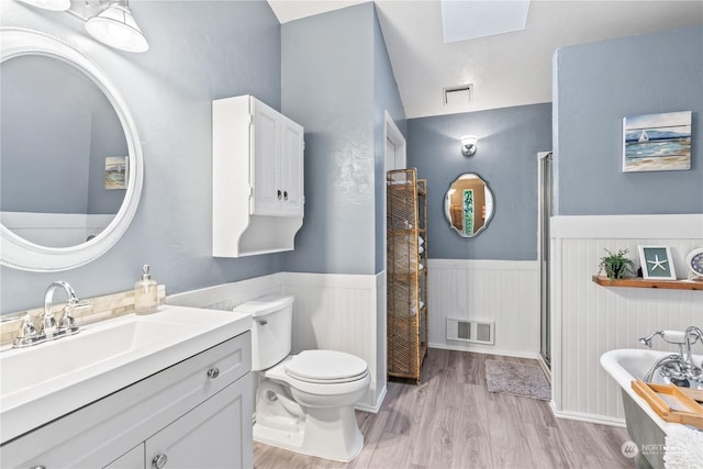 bathroom with toilet, wood-type flooring, vanity, and lofted ceiling