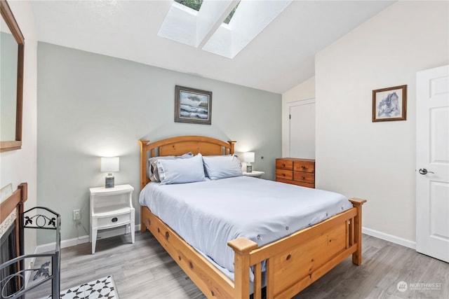 bedroom with light hardwood / wood-style flooring and vaulted ceiling with skylight