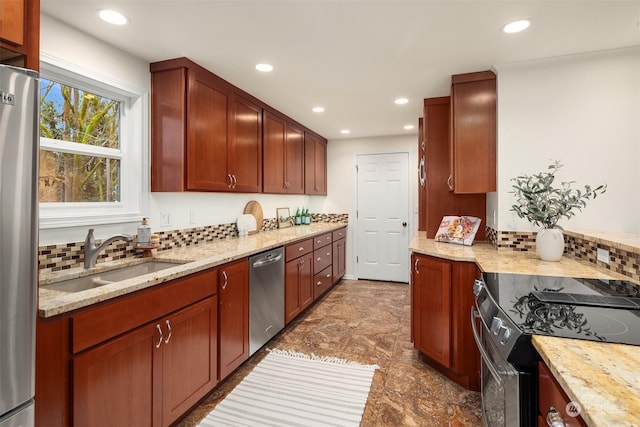 kitchen with light stone counters, stainless steel appliances, and sink