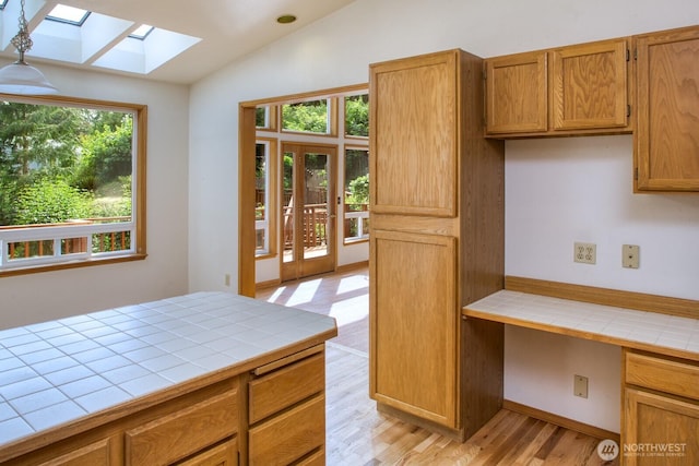 8917 SE Mcbreen Ln, Port Orchard, WA 98367 - kitchen with tile countertops, lofted ceiling, a skylight, light wood-style flooring, and brown cabinets